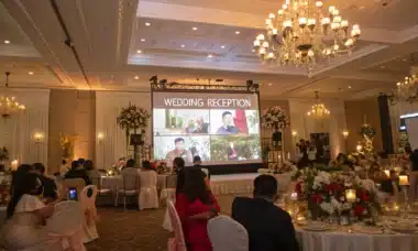 Un mariage en salle avec un écran géant diffusant un message vidéo des proches, ambiance chaleureuse et émotive.